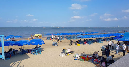 Nhiều người nằm tắm nắng trên ghế, vui chơi trên bờ cát khi đi du lịch Long Hải